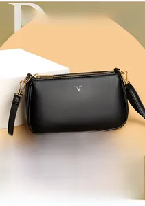 Close-up of black lychee grain leather crossbody bag with silver deer head logo and gold hardware