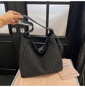 Détail du grand sac cabas noir avec des plis verticaux uniques et une texture gaufrée