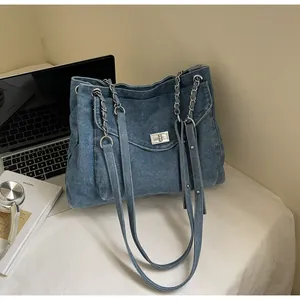 Detail of blue denim tote bag with silver metal twist lock and mixed chain leather straps