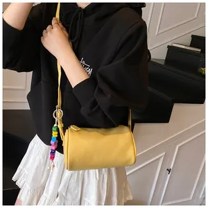 Detail of yellow lychee leather barrel bag with colorful beaded strap charm decoration
