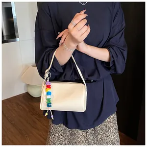 Detail of off-white cylinder bag with lychee texture and rainbow letter charm
