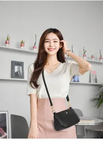 Close-up of black lychee grain leather crossbody bag with golden fox logo on a model