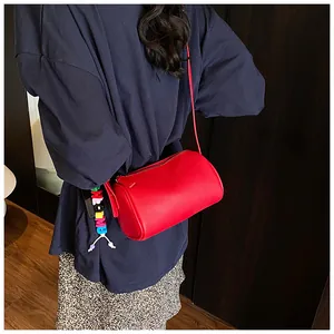 Detail of red lychee leather Boston bag with a colorful alphabet bead charm on model