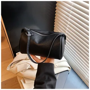 Close-up of black lychee grain leather pillow bag with silver zipper and shoulder strap