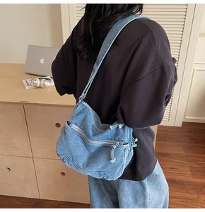 Dettaglio borsa a tracolla in denim lavato blu con design multitasche e tracolla regolabile