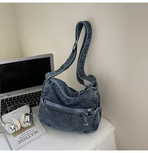 Dettaglio della borsa a tracolla in denim lavato blu con cerniere e ampia tracolla
