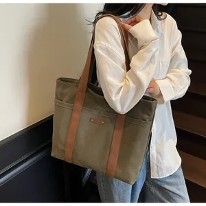 Grand sac cabas en toile vert olive porté par un mannequin pour un look quotidien