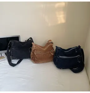 Tre borse a tracolla in denim vintage con tasche multiple esposte su una scrivania