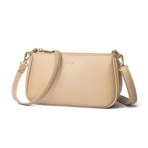 Minimalist beige lychee grain leather crossbody bag with golden deer head logo accent