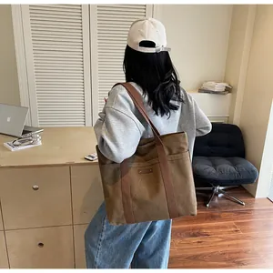 Vue détaillée du grand sac cabas en toile marron avec poches avant et larges bandoulières