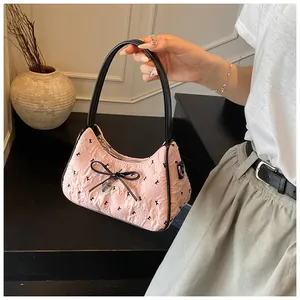 Detail of pink polka dot bag with black ribbon bow and silver heart pendant detail