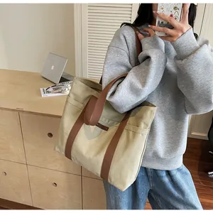 Détail d'un grand sac cabas en toile kaki avec poches latérales et sangles marron