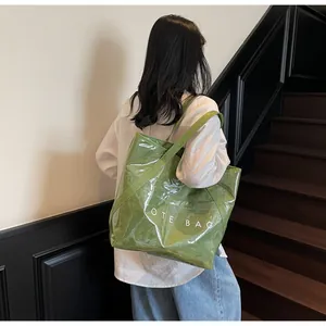 Detail einer großen grünen glänzenden Tragetasche mit weißem TOTE BAG Text Aufdruck