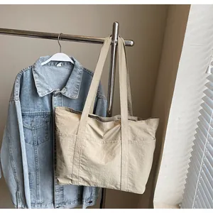 Detailed close-up of a large beige nylon tote bag showing pockets and fabric texture