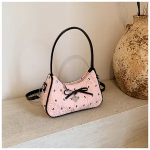 Close-up of pink pleated fabric handbag with black bow decoration and silver heart charm