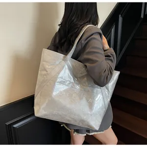 Detail der silbernen Metallic-Tasche mit TOTE BAG Aufdruck an der Schulter