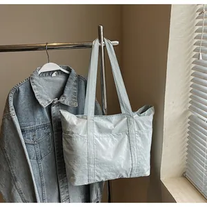 Detail of light blue textured nylon tote bag with side pocket hanging on rack