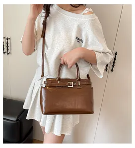 Détail d'un sac bandoulière marron foncé avec boucle métallique et bandoulière sur un mannequin