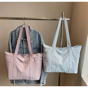 Detail of solid color nylon tote bags in pink and light blue with side pockets