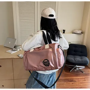 Detalle de bolsa de viaje de nailon rosa impermeable con logo y correa ajustable