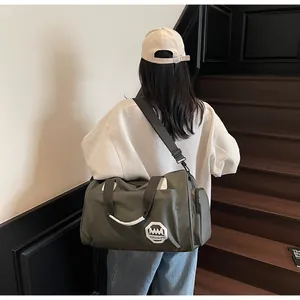 Vista trasera de modelo llevando una bolsa de viaje impermeable verde oliva de gran capacidad