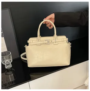 Gros plan du sac à main crème texturé avec boucle décorative et poignée supérieure chic