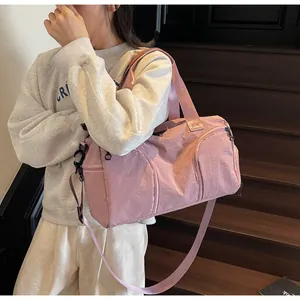 Pink nylon travel bag detail showing smooth texture, reinforced handles and zip pockets