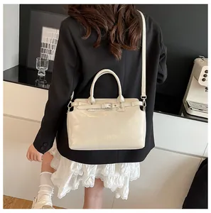 Détail du sac à bandoulière blanc crème montrant le cuir brillant et la boucle de ceinture