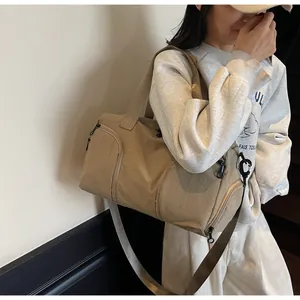 Detail view of khaki nylon travel bag with reinforced handles and adjustable shoulder strap