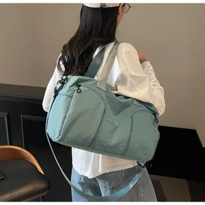 Rear view of a light sage green nylon travel bag worn by a model in a minimalist setting