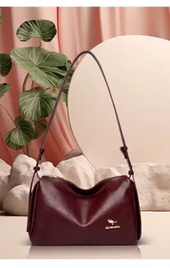 Detail of burgundy leather Boston bag with golden kangaroo logo on satin background