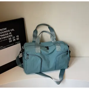 Macro detail of teal nylon travel bag featuring dual arc-shaped front zipper pockets