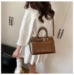 Détail du sac à main carré en cuir marron foncé avec boucle argentée et bandoulière réglable