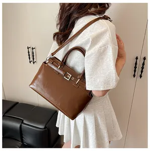 Détail macro d'un sac carré en cuir marron foncé avec boucle métallique et texture fine