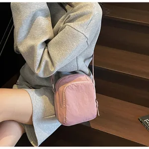 Details der rosa Mini-Umhängetasche aus Nylon mit Reißverschlüssen und verstellbarem Gurt