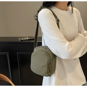 Nahaufnahme einer olivgrünen Handy-Stofftasche, die von einem asiatischen Modell getragen wird