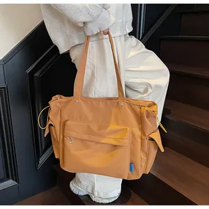 Detail of ginger yellow crossbody bag showing zip pockets and side drawstring toggles