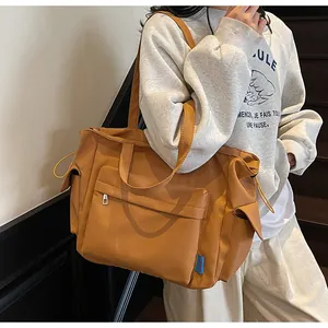 Detail of large canvas crossbody bag featuring side drawstring pockets and zipper pocket