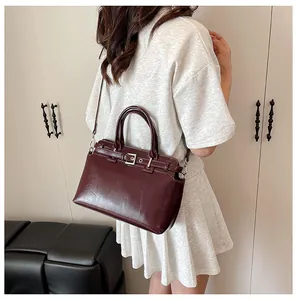 Détail du sac à main bordeaux en cuir brillant avec bandoulière et boucle décorative