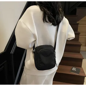Detail einer minimalistischen schwarzen Nylon-Umhängetasche mit Reißverschlusstaschen