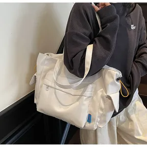 Detail view of white canvas crossbody bag featuring side pockets and utility drawstrings
