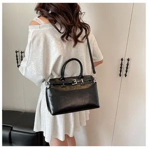 Détail d'un sac bandoulière noir brillant avec boucle argentée porté par un mannequin