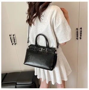 Détail d'un mini sac carré noir en similicuir avec double poignées et bandoulière