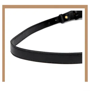 Detailed close-up of smooth black leather handbag strap with gold metallic hardware