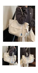 Detail of large white canvas tote bag with yellow drawstrings and multiple pockets