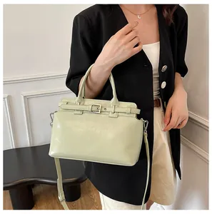Détail d'un sac bandoulière vert clair avec poignées et finitions argentées