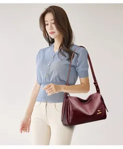Detail view of burgundy leather boston bag with golden kangaroo logo and adjustable strap