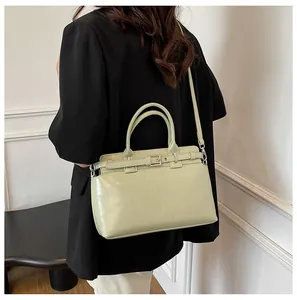 Détail d'un sac à main en cuir vert clair avec boucle en métal et bandoulière sur modèle
