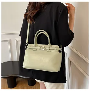 Détail du petit sac carré vert clair avec bandoulière réglable sur blazer noir chic