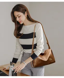 Detail of vintage brown leather Boston bag with gold logo and adjustable shoulder strap